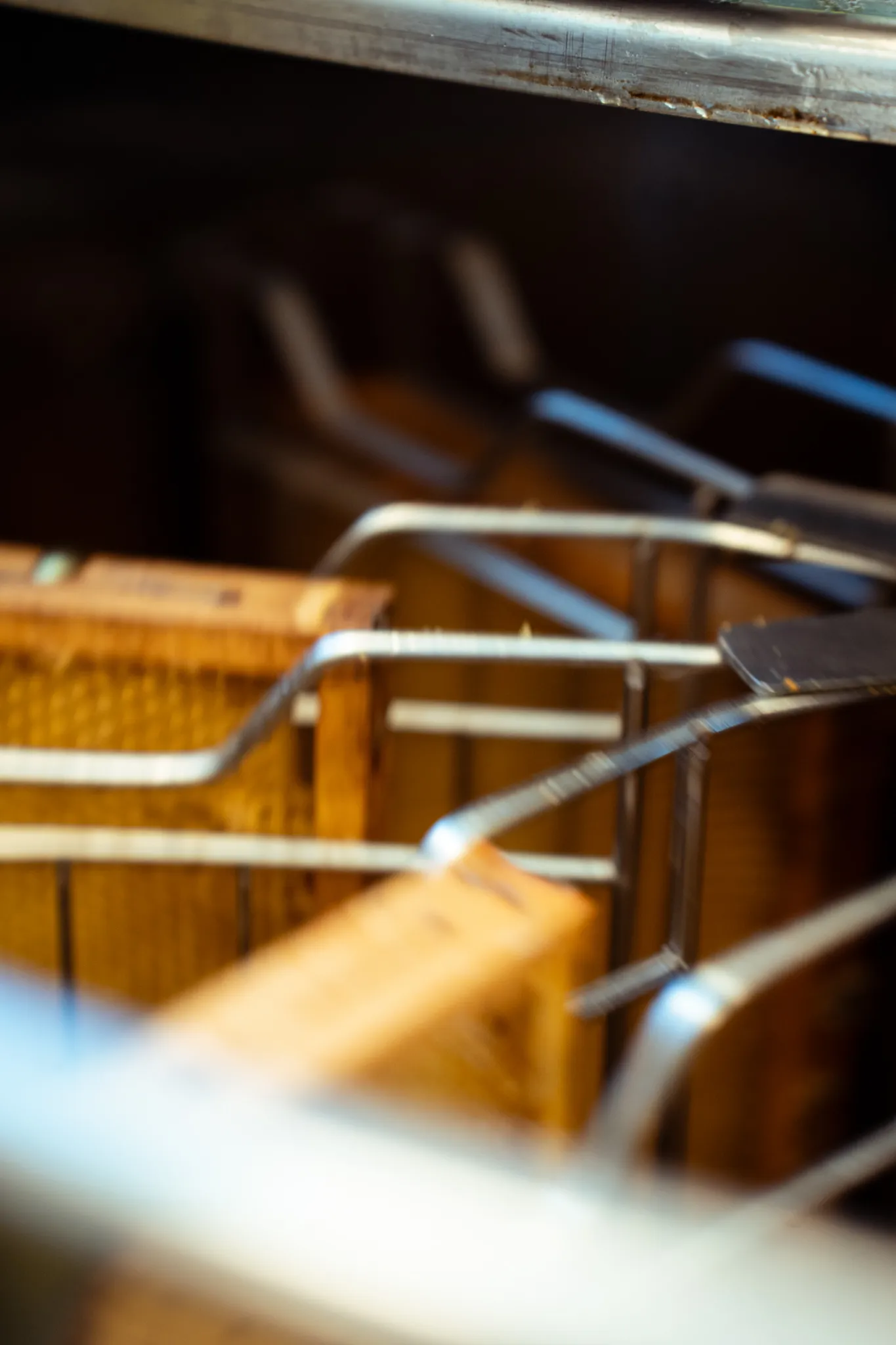 Close-up of several wooden frames with bent metal wires in a dark setting.