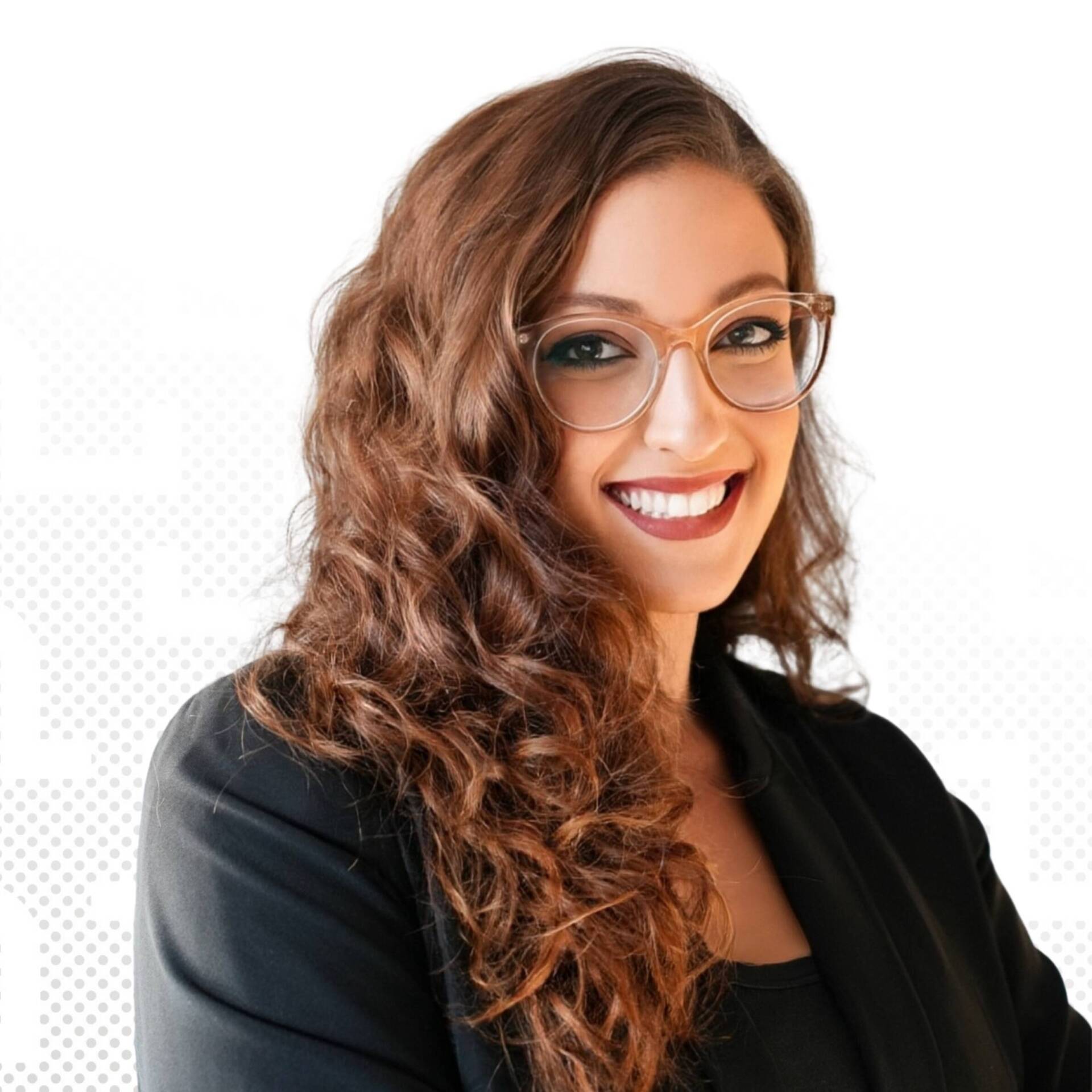 Porträt einer Frau mit lockigem braunem Haar und Brille in schwarzem Blazer vor weißem Hintergrund.