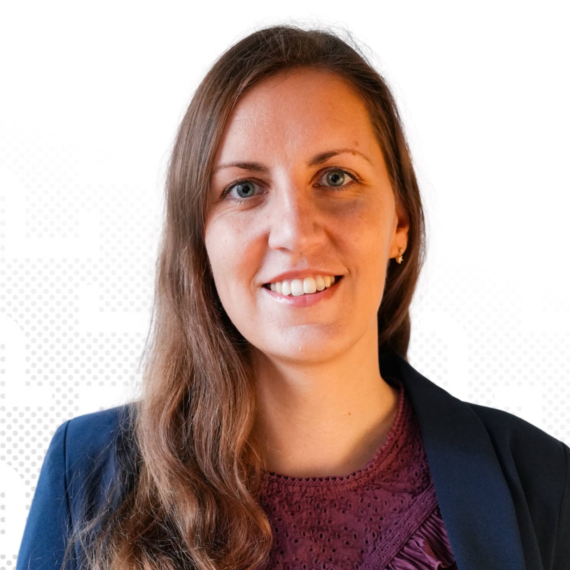 A professional business portrait of Shirley Tramper with brown hair in a blazer against a light-coloured background.